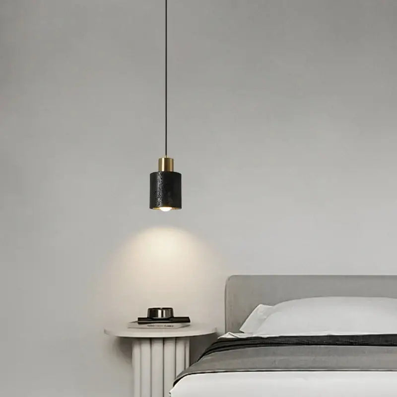 Modern black travertine led pendant light with textured surface and brass accents hanging above bedside table decorbites black travertine