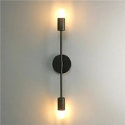 Modern black metal two arm led wall lamp with cylindrical fixtures and circular base for bedroom vanity lighting