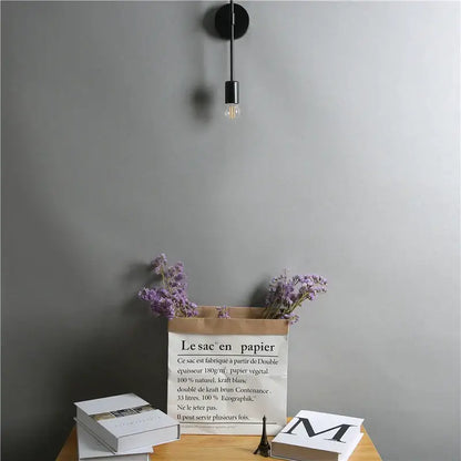 Modern black two arm led wall lamp with slender stem and exposed filament bulb for bedroom vanity lighting