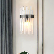 Modern black wall lamp with sleek metal ring and icicle crystal rods emitting warm light for dining room use