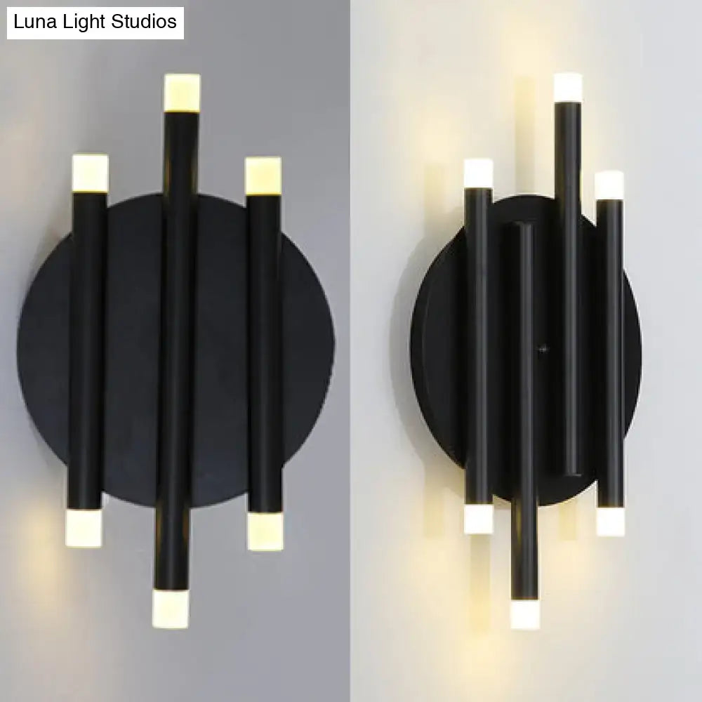 Modern black wall light with round backplate featuring three vertical cylindrical arms and frosted white led light caps