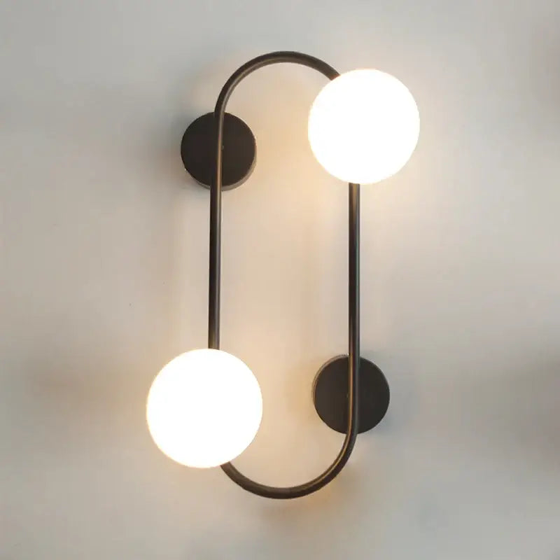 Modern black wall sconce with frosted glass globes featuring two glowing bulbs for bedroom decorbites brass led style
