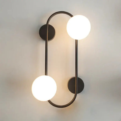 Modern black wall sconce with frosted glass globes featuring two glowing white spherical bulbs for bedroom decorbites brass led use