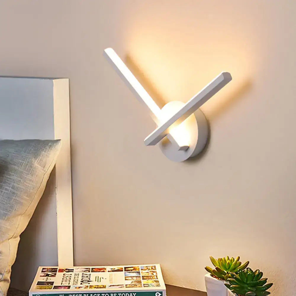 Modern black and white acrylic cross wall sconce with sleek angular arms and warm white light for bedroom use