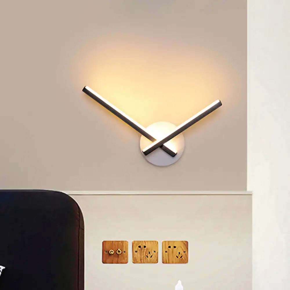 Modern black and white acrylic cross wall sconce with two metallic arms and warm white light for bedroom use