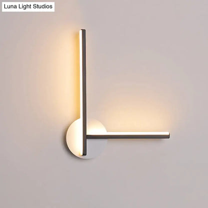 Modern minimalist l-shaped acrylic cross wall sconce with sleek metallic arms and warm white light for bedroom use