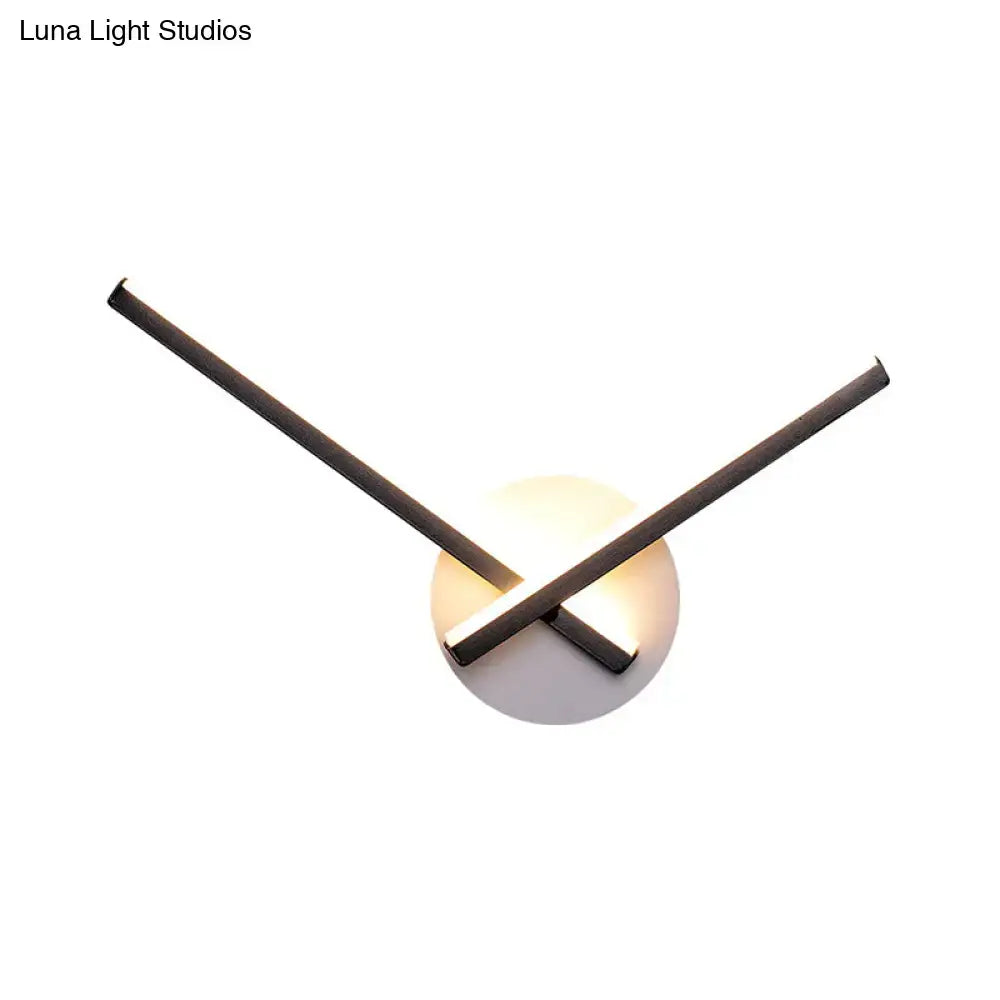Minimalist modern black and white acrylic cross wall sconce with intersecting rods and warm white glowing base light
