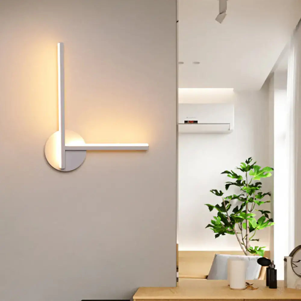 Modern black and white acrylic cross wall sconce with a white minimalist design emitting warm white light for bedroom use