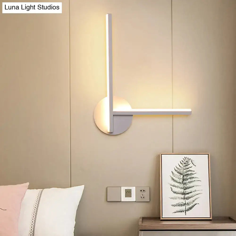 Modern black and white acrylic cross wall sconce with sleek vertical arm emitting warm white light for bedroom use