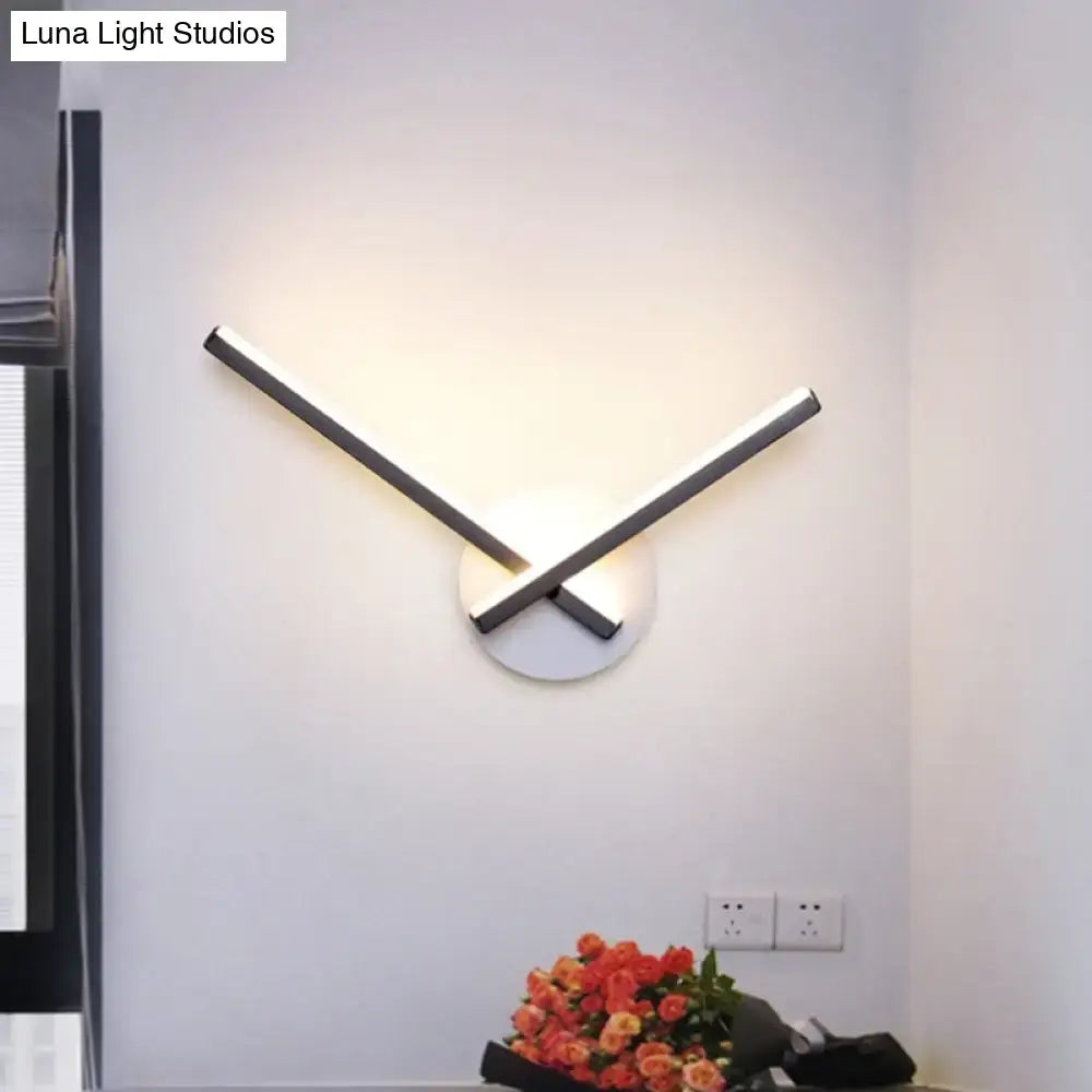 Modern black and white acrylic cross wall sconce with sleek angular arms and warm white light for bedroom use