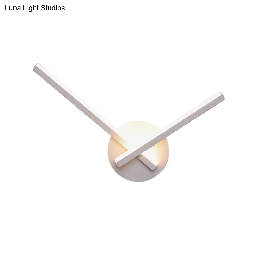 Modern black and white acrylic cross wall sconce with sleek intersecting arms and warm white glowing circular base
