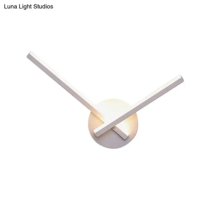Modern black and white acrylic cross wall sconce with sleek intersecting arms and warm white glowing circular base