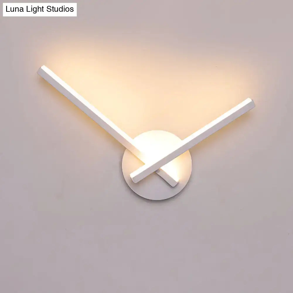 Modern black and white acrylic cross wall sconce with intersecting arms emitting warm white ambient light for bedroom use