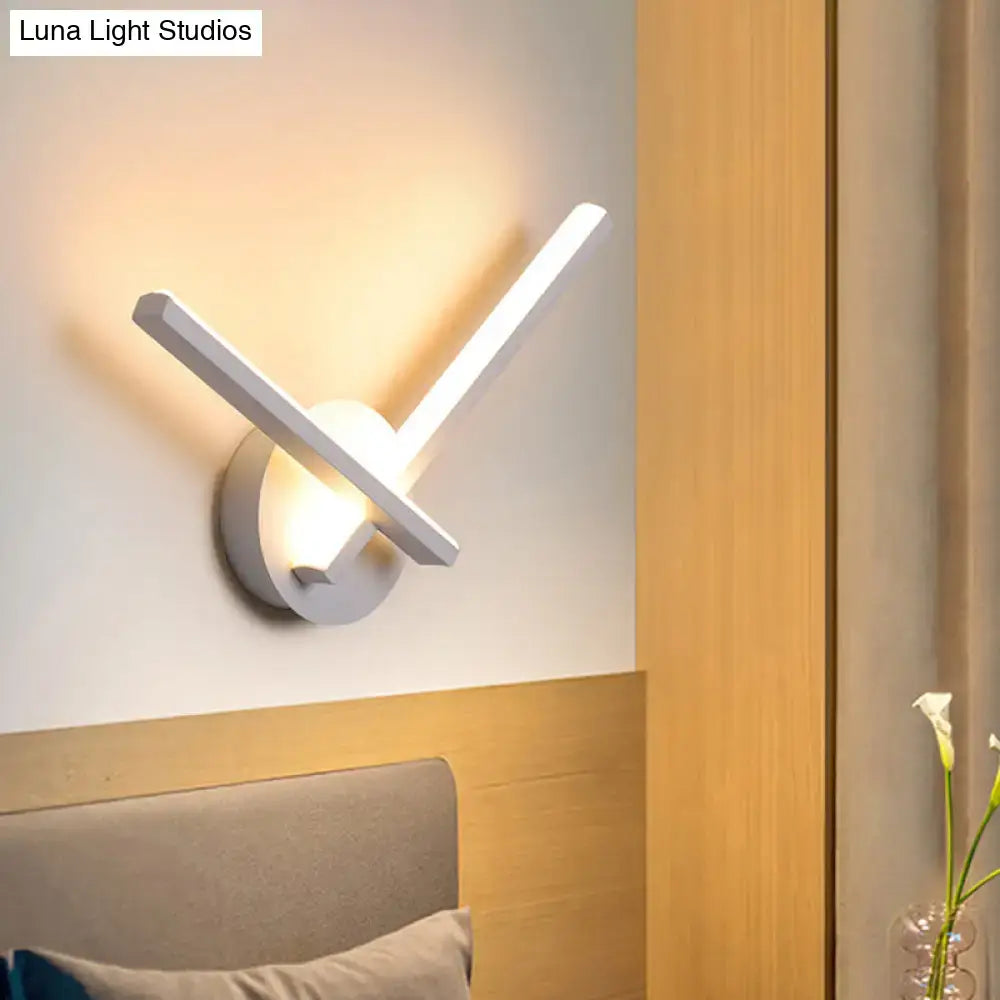 Modern black and white acrylic cross wall sconce with two angular arms emitting warm white light for bedroom use