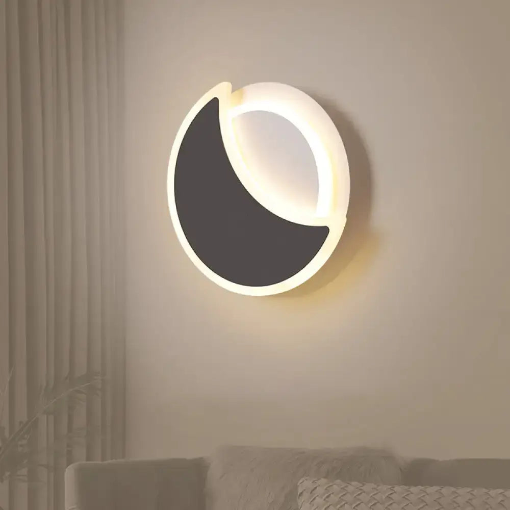 Modern black white acrylic eclipse wall sconce with crescent shape emitting warm ambient light for bedroom use