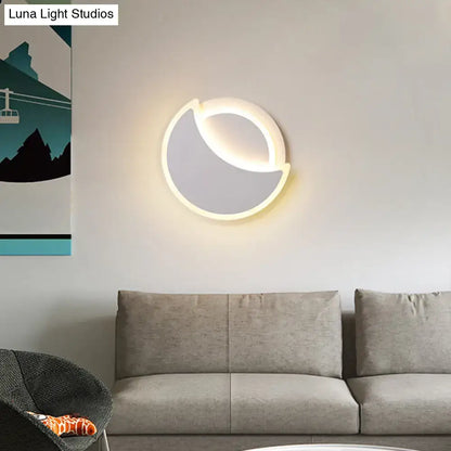 Modern black and white acrylic eclipse wall sconce with crescent shape and soft glowing light for bedroom use