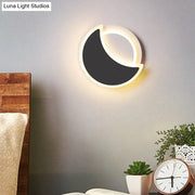 Modern black and white acrylic wall sconce shaped like a crescent moon emitting warm ambient bedroom light