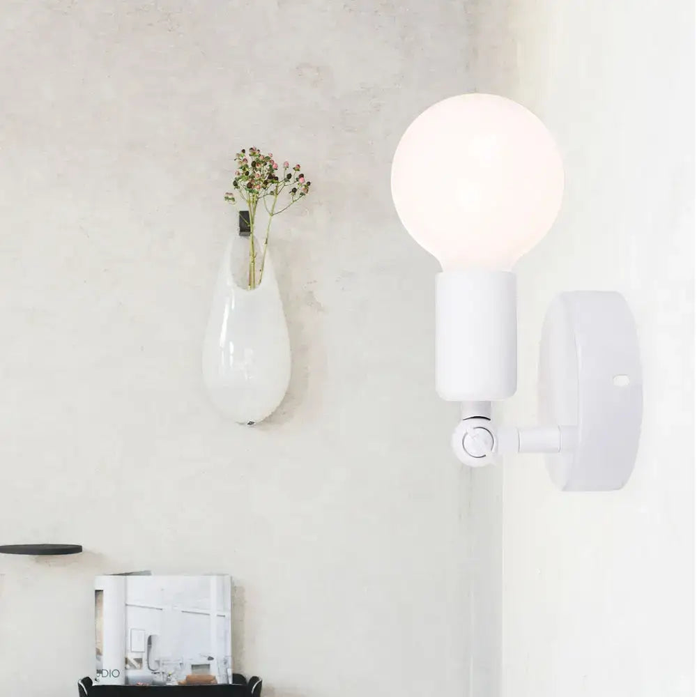 White spherical bulb mounted on a modern black and white adjustable wall lamp holder bedroom sconce with arm