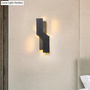 Modern black and clear acrylic wall mount light with angular design emitting warm ambient light for bedroom use