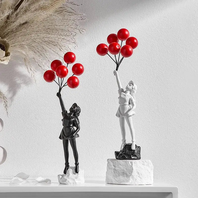 Two contrasting black and white resin balloon girl graffiti statues each holding vibrant red balloons for decor