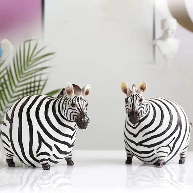 Two chubby black and white striped big belly zebra resin sculptures with detailed faces for modern living room decorbites decor