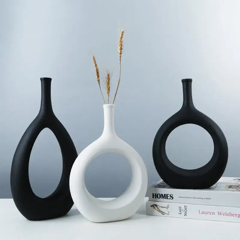 White ceramic decorbites ceramic vase with circular cutout and slender neck holding dried wheat for living room decor