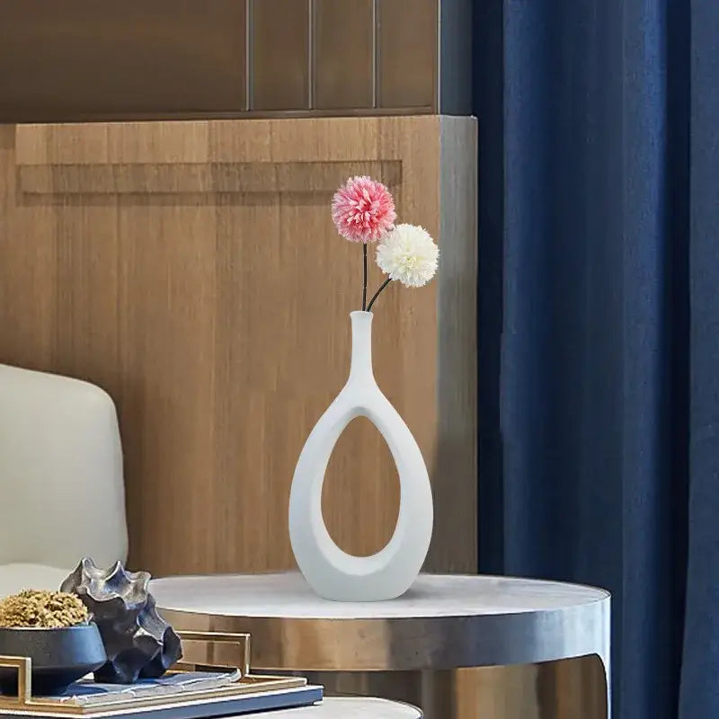 Modern black and white decorbites ceramic vase with teardrop shape and oval cutout holding pink and white pom-pom flowers