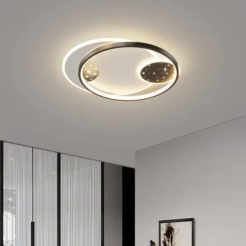 Modern black decorbites living lamp chandelier with circular black metal frame and glowing starry celestial discs for dining room