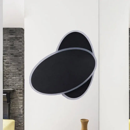 Modern black and white double oval wall sconce lamp with sleek silver outlined overlapping ovals for bedside lighting
