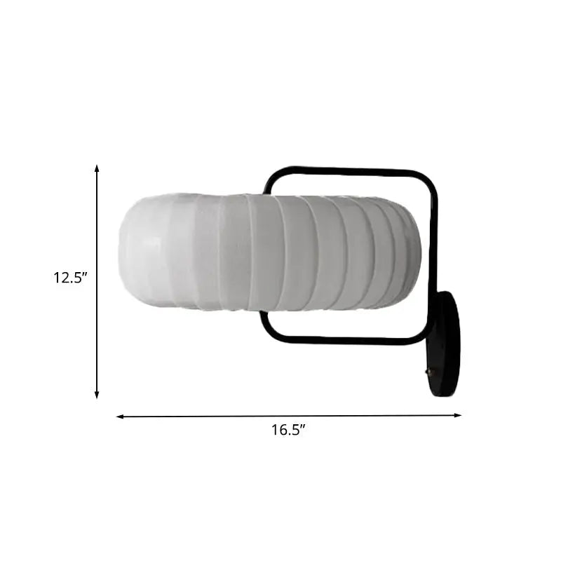 A modern black and white gathered fabric pumpkin wall sconce with a white ribbed glass lamp and black metal frame