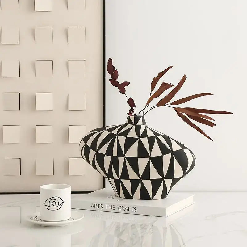 A sleek black and white geometric diamond ceramic vase with bulbous body and dried foliage for living room decor