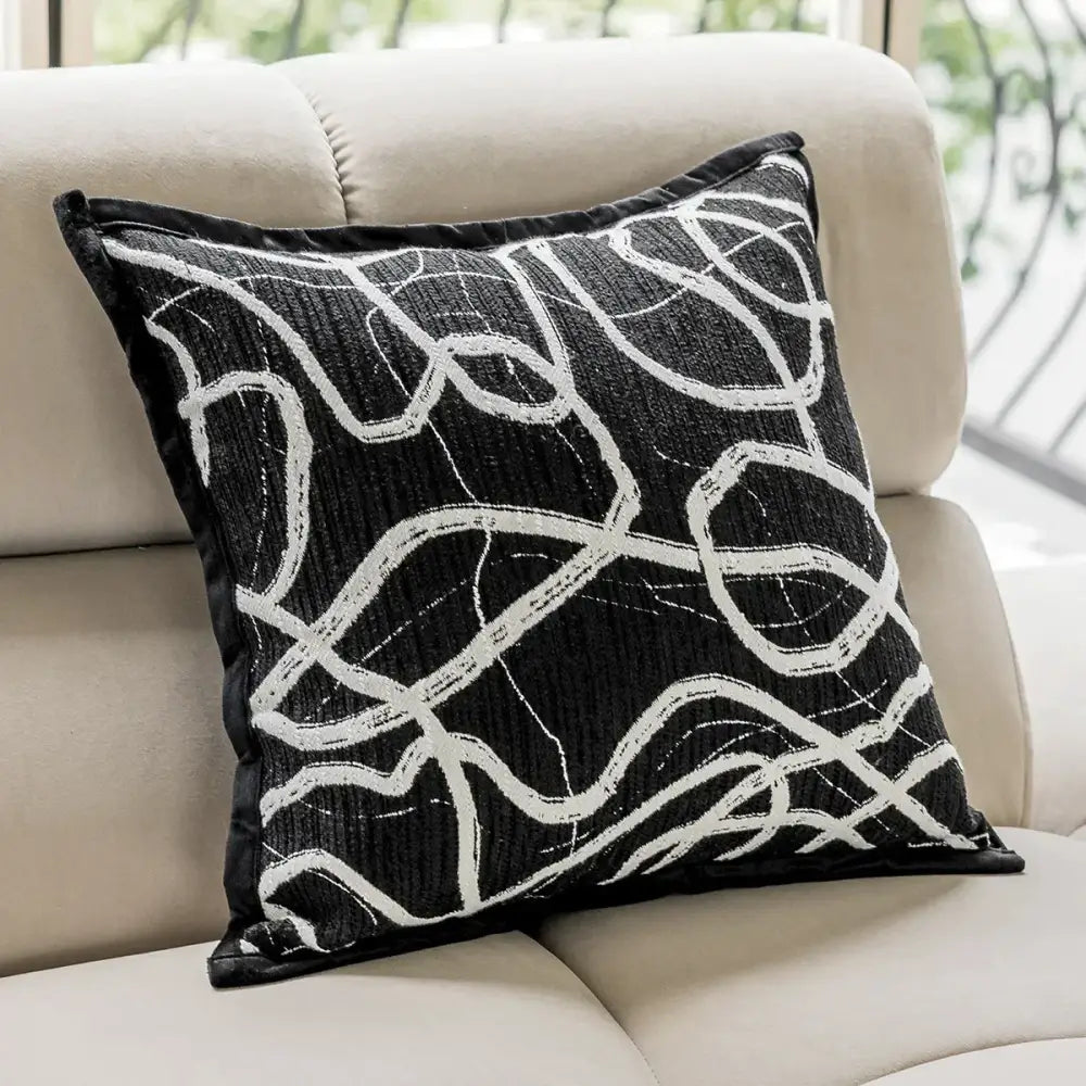 Modern black and white geometric jacquard cushion cover with black throw pillow featuring white abstract line embroidery and velvet trim