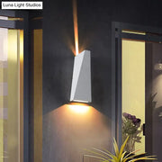 Modern black and white geometric nord wall sconce with warm amber light casting focused beams upward and downward