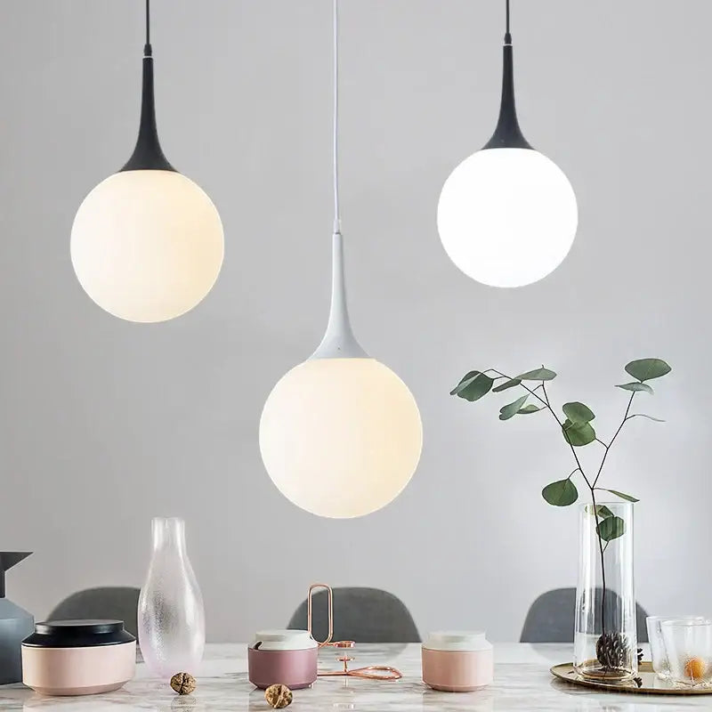 Three modern pendant lights with black and white stems and frosted glass ball led globes for living room decorbites