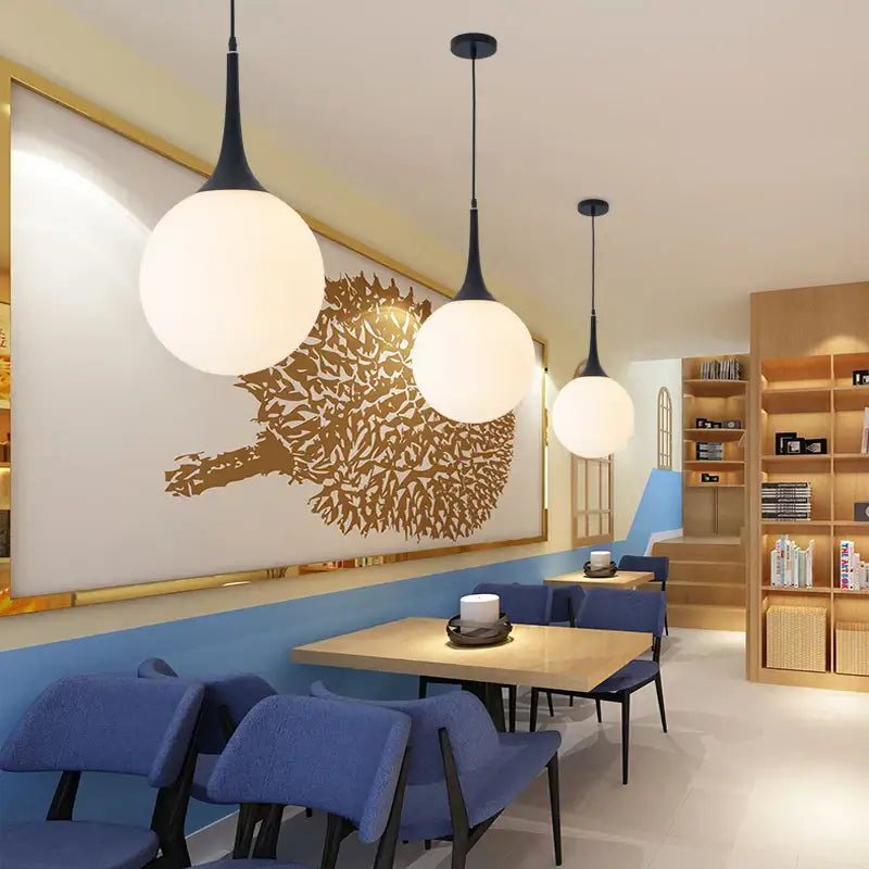 Three modern decorbites glass ball pendant lamps with black stems and opaque white shades for dining room lighting