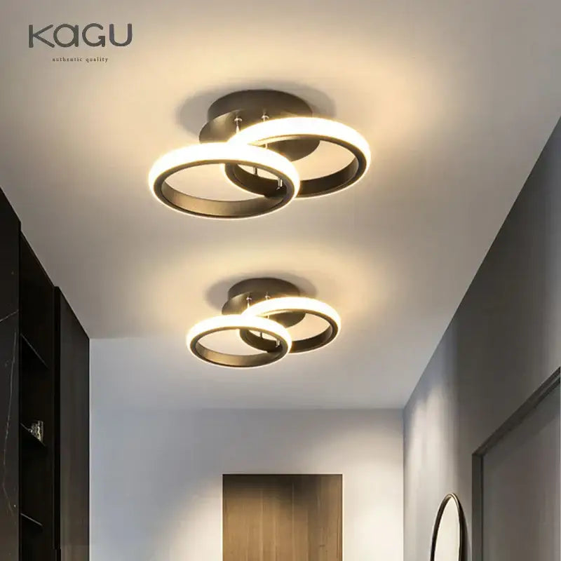 Modern black and white decorbites led ceiling lamp with interlocking rings in brushed bronze emitting warm ambient glow