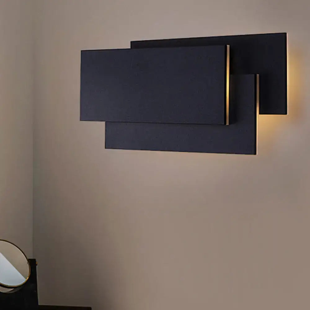 Modern black wall lamp with overlapping geometric panels and warm light glow fixture height 5in for bedroom use