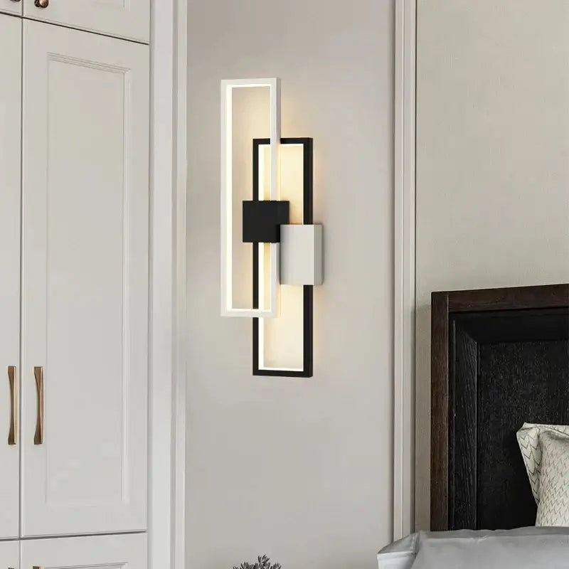 Modern black and white led wall lamp with sleek geometric frame and layered panels emitting warm ambient light
