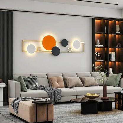 Modern black and white led wall lamps featuring geometric illuminated discs in orange black and white within gold frame