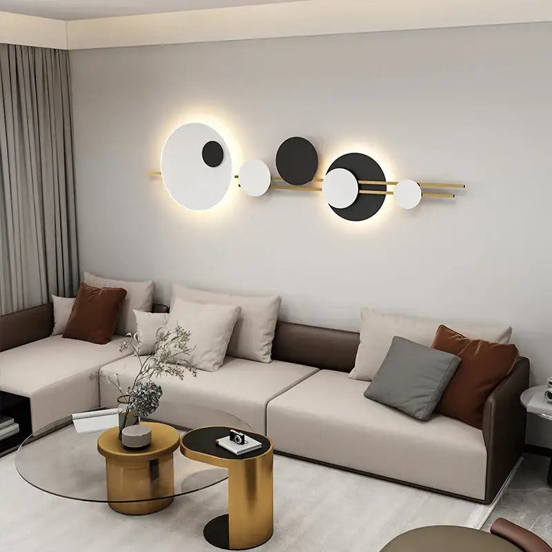 Modern black and white led wall lamps with geometric circular discs and gold-toned rods emitting warm glow
