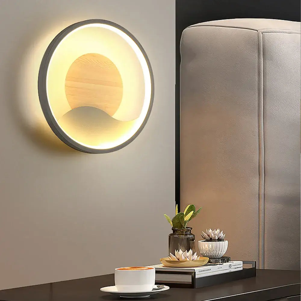 Modern black and white led wall light with a circular black frame, wooden disc center, and warm ambient led lighting