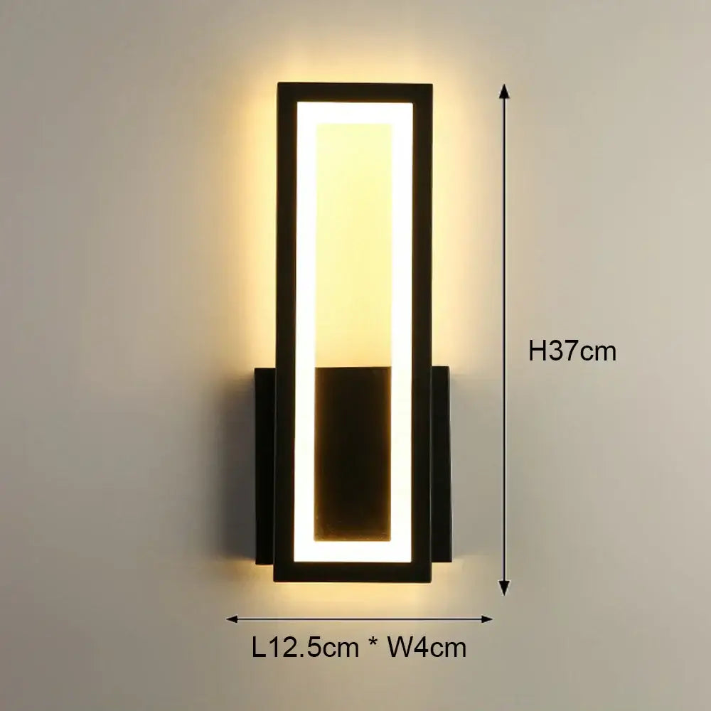 Modern black-framed led wall light with rectangular panel emitting warm yellow illumination for bedroom use