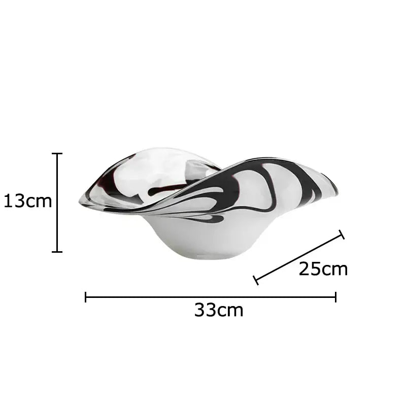 A sleek modern glass fruit plate with a flowing black and white marbled design for dining room use