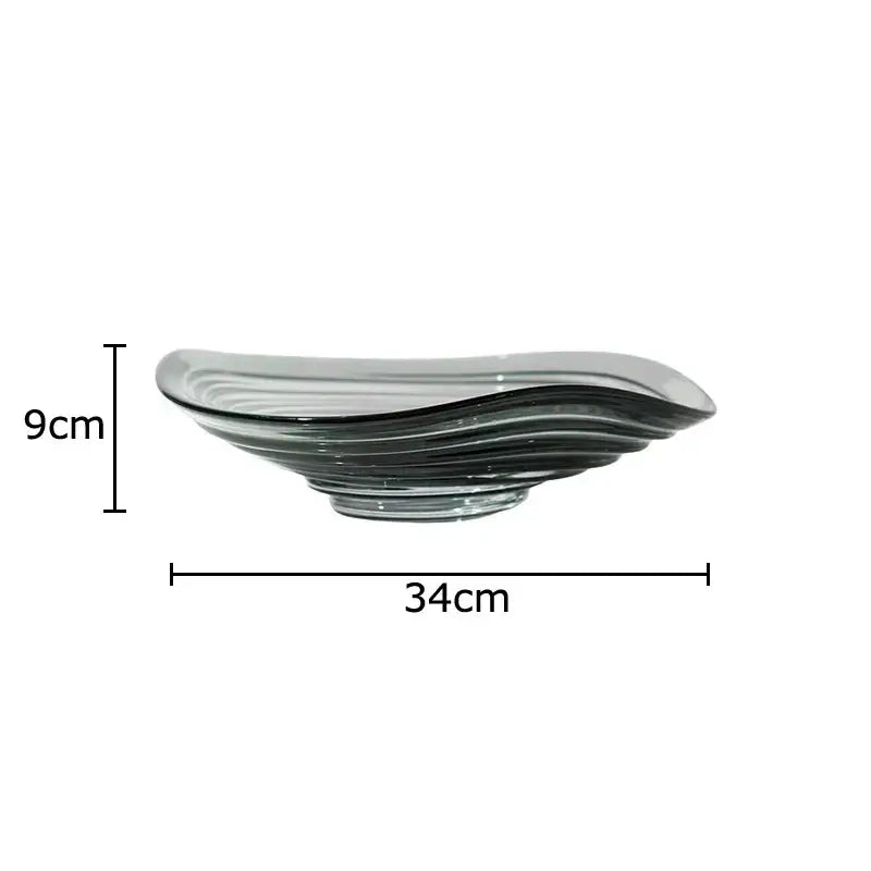 A sleek translucent gray glass fruit plate with wavy layered design and smooth curved edges for dining room use