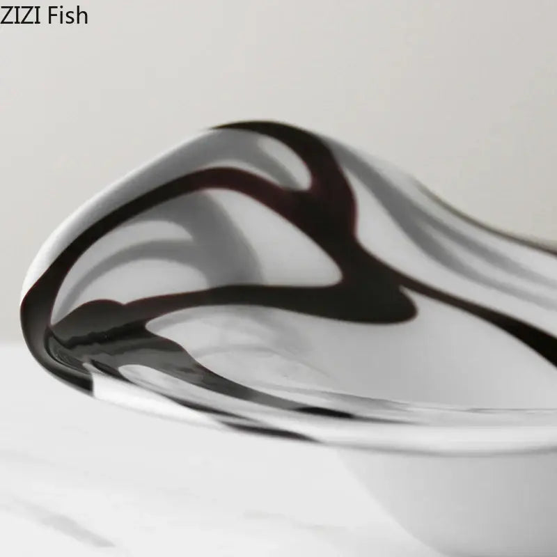 A sleek modern glass fruit plate with black and white marbled swirls designed as a dining room bowl
