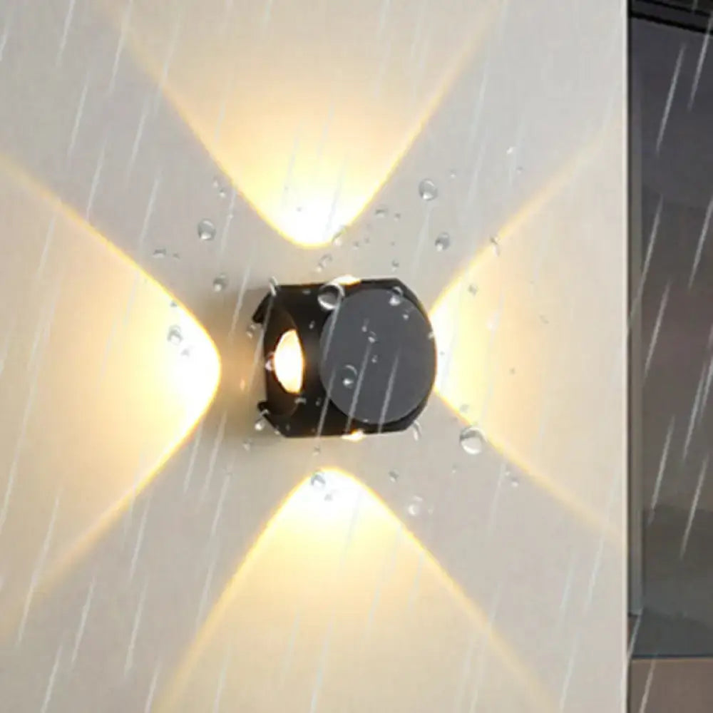 Modern black mini cube wall lamp with sleek geometric design emitting warm yellow light for living room use