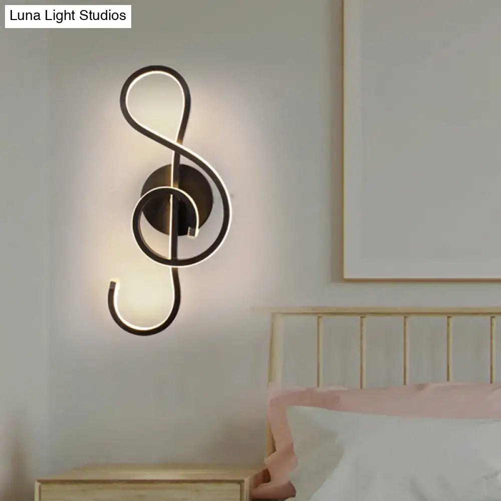 Modern black wall lamp shaped like a musical note with acrylic shade emitting warm light for bedroom use