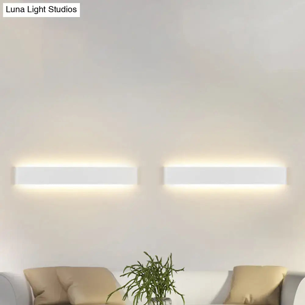 Two minimalist white wall lamps with rectangular metal shade emit a warm glow in a modern living room light fixture
