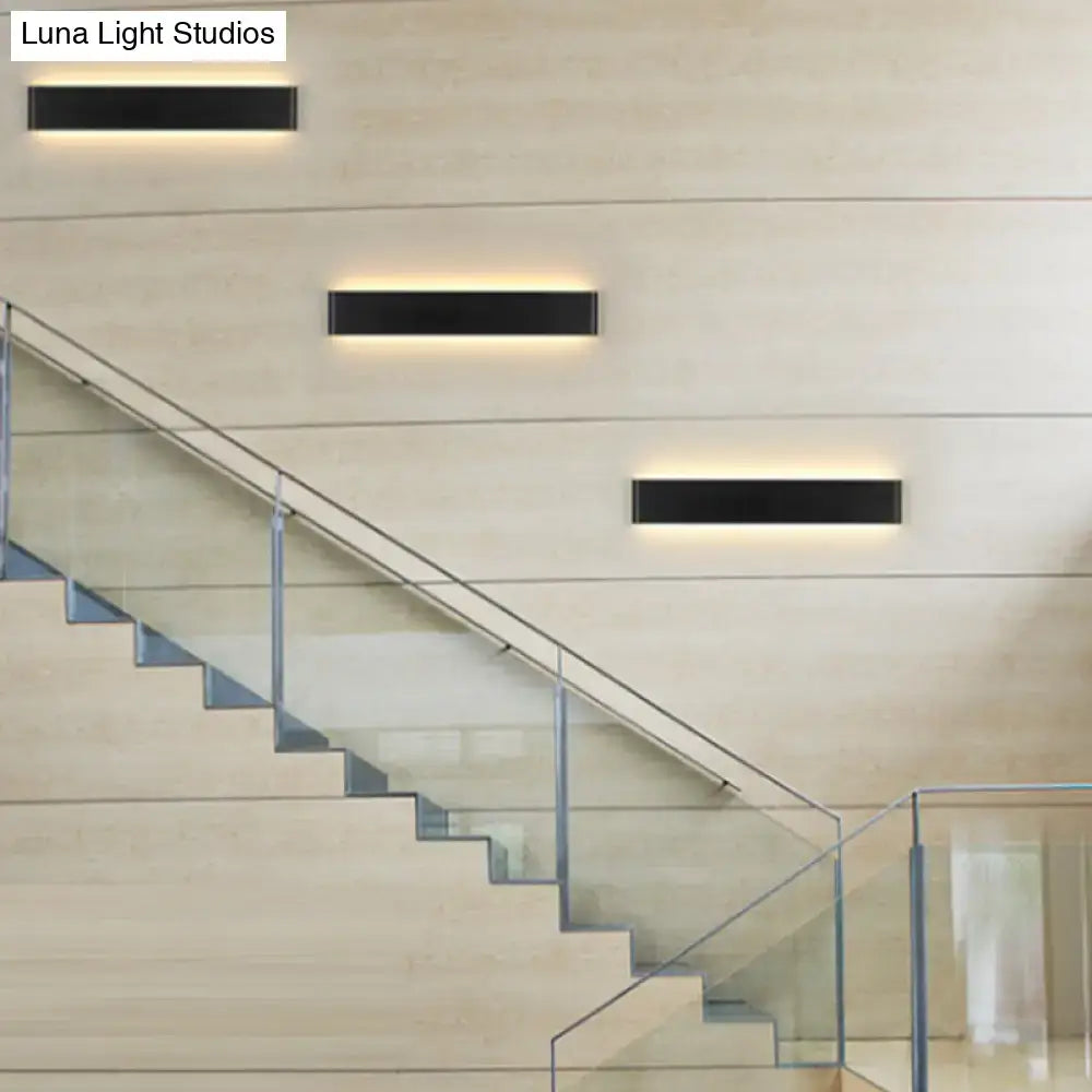 Three sleek black wall lamps with rectangular metal shades provide warm ambient lighting for living room spaces