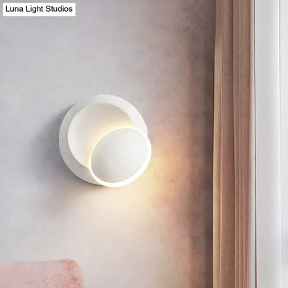 Modern black and white rotating eclipse wall lamp with a sleek white rotating circular sconce emitting warm light